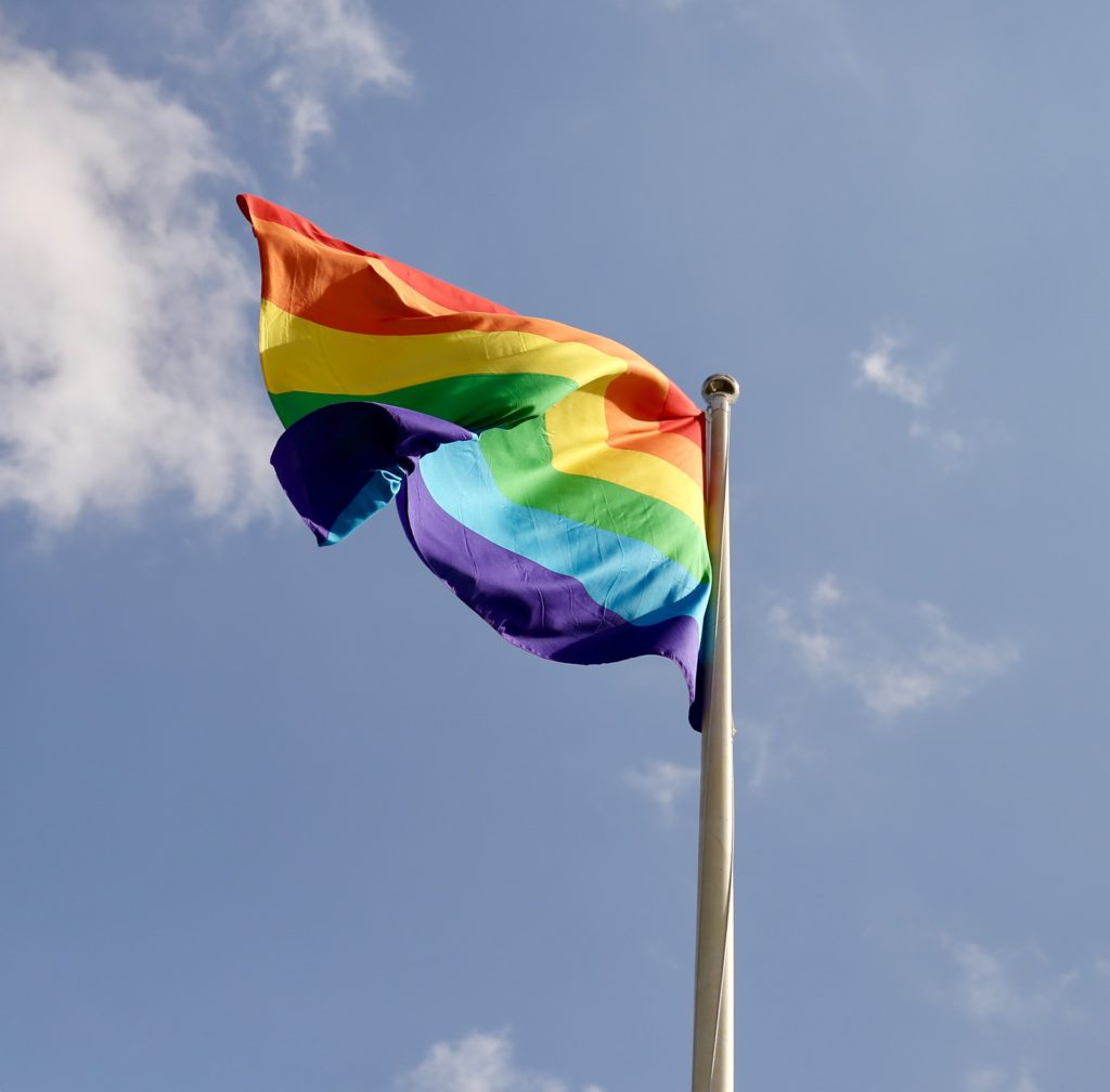 Flagga med regnbågens färger.