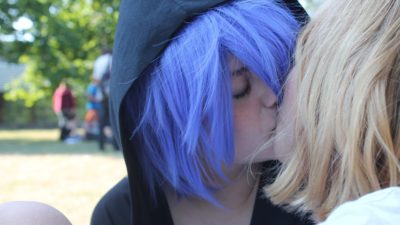 En tjej med blått hår kysser en tjej i blont hår.