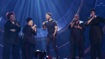 John Lundvik och hans gospelkör tar i och sjunger på scenen under Melodifestivalen.