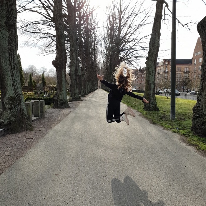 Tjej hopparpå en väg på en kyrkogård