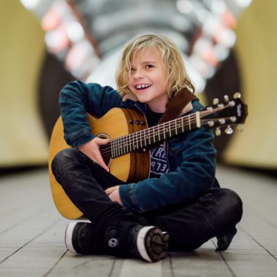 Oscar sitter med en gitarr i famnen