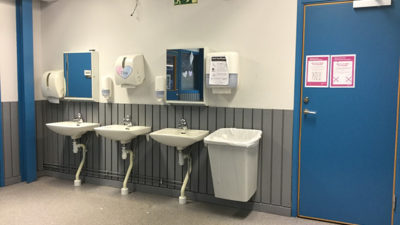 Foto från ingången till skolans matsal. Lappar har satts upp på dörren och väggen.