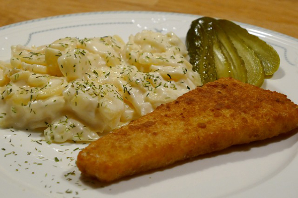 En tallrik med panerad fisk och potatisgratäng.