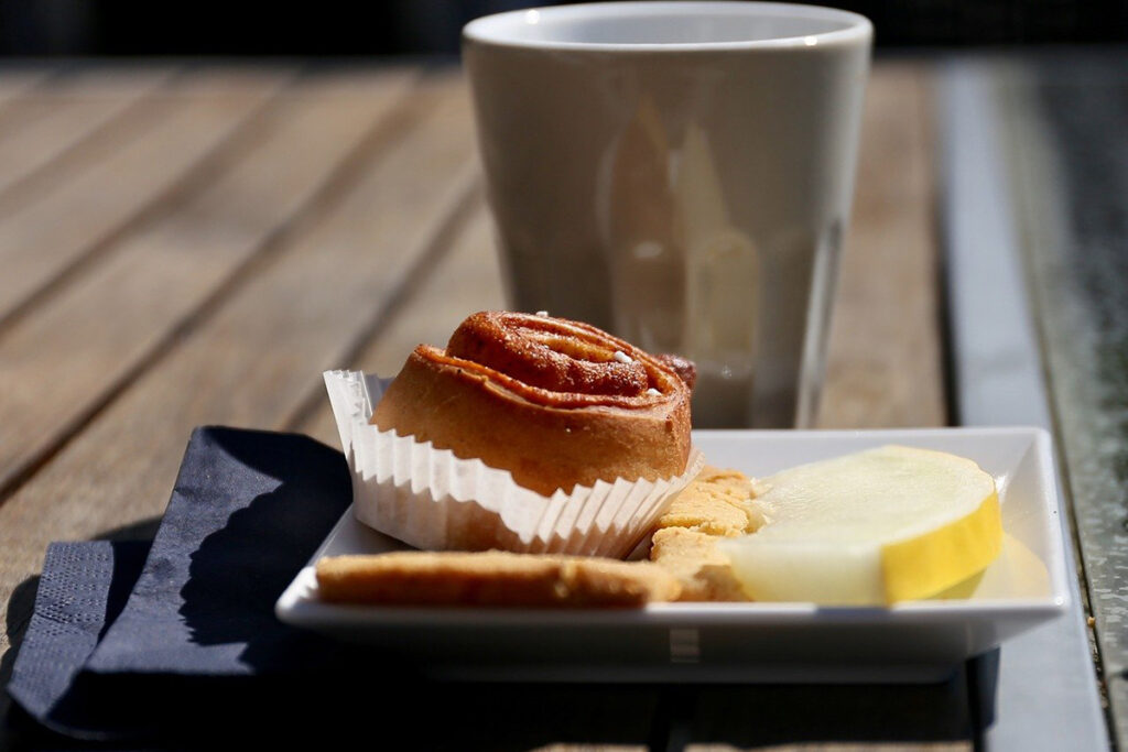 Kanelbulle, melon och en kaffekopp på en brygga.