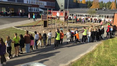 Skolans elever är samlade i långa led på skolgården.